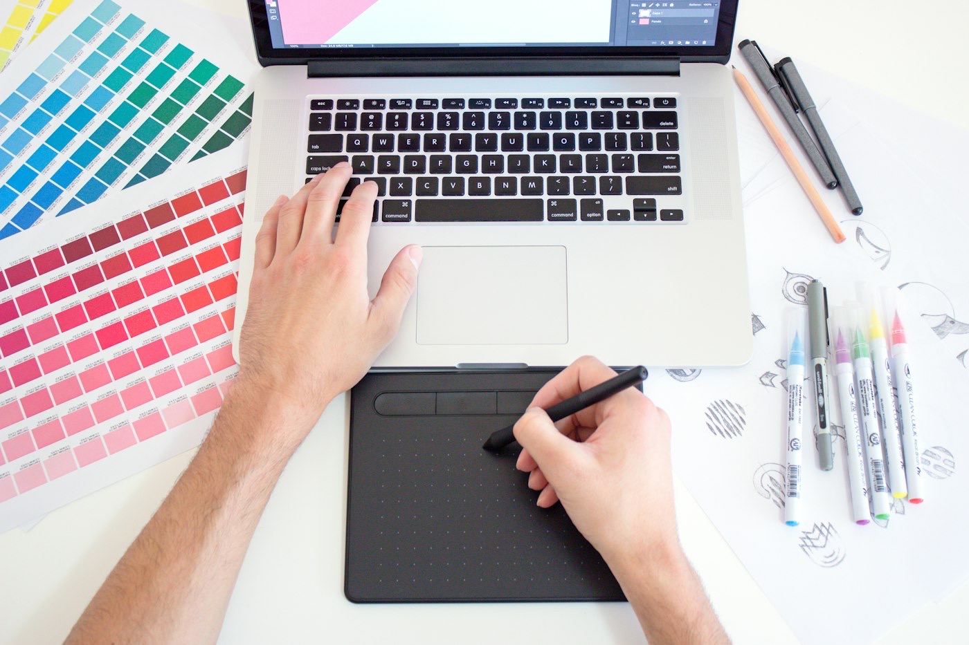 Nuancier, feutres et tablette graphique sur un plan de travail